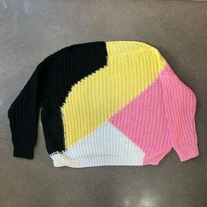 Hand knit geometric sweater in black, yellow, pink, and white.